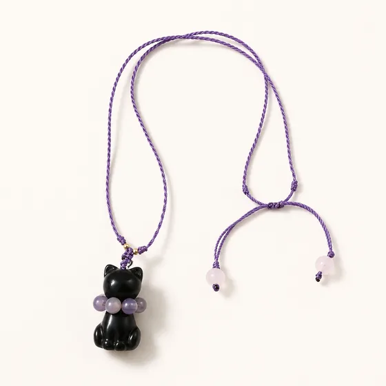 A carved jade cat, amethyst at the collar, rose quartz at the ends of the cord.